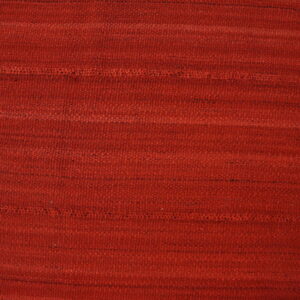 Textured red rug with visible horizontal bands and stitching next to light-colored wood flooring.