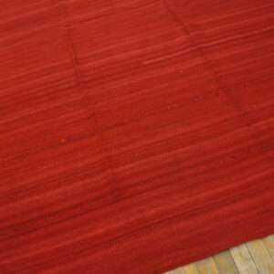 Deep red, textured flat-woven rug with subtle horizontal stripes resting on light wood flooring.