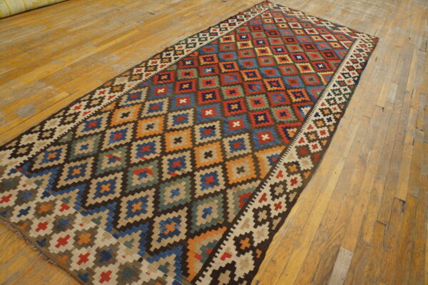 Multicolor flatweave runner rug with repeating geometric diamonds displayed on distressed wood floors.