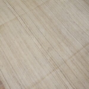 Natural beige woven rug with subtle vertical texture variations rests on hardwood floors.