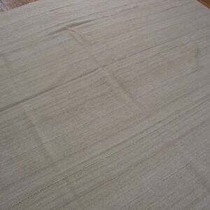 A large, textured flatweave rug in a natural beige color lies on dark wood floors.