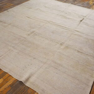 Light neutral-toned flatweave rug featuring stitched panels on rustic wood flooring.