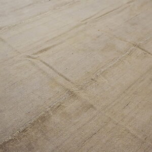 Neutral beige flat-weave rug with visible stitched seams forming a rectangular patchwork design.