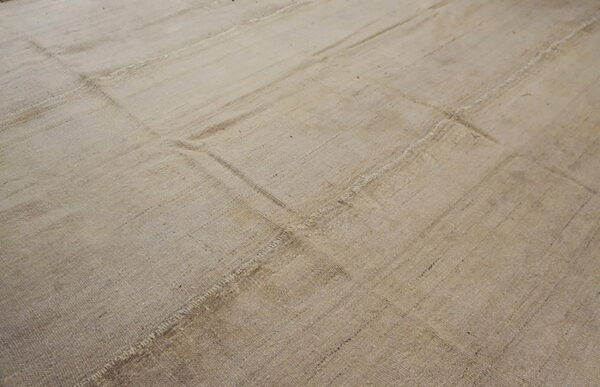 Neutral beige flat-weave rug with visible stitched seams forming a rectangular patchwork design.