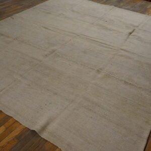 Light beige flatweave area rug with sectional seams displayed on dark hardwood flooring.
