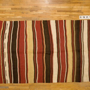 Low-pile striped rug in rich brown, rust, cream, and tan colors laid on light natural wood flooring.