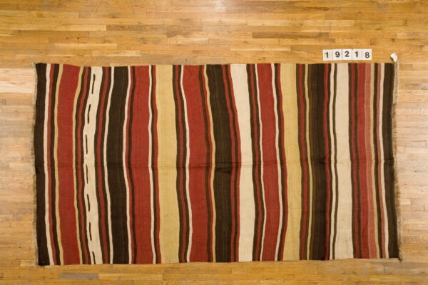 Low-pile striped rug in rich brown, rust, cream, and tan colors laid on light natural wood flooring.