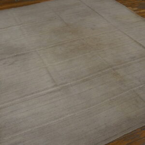 Muted gray-taupe flatweave rug featuring subtle horizontal banding on distressed wood planks.