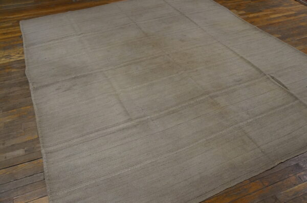 Muted gray-taupe flatweave rug featuring subtle horizontal banding on distressed wood planks.