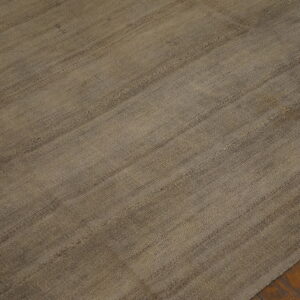 A mottled brown and gray flatweave rug with horizontal seams is laid over dark hardwood floors.