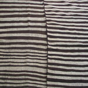 Brown and white striped rug composed of two vertical panels joined by stitching, resting on a wood floor.