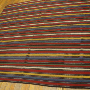 Colorful striped rug with red, blue, yellow, black, and white bands lies on light wooden floors.