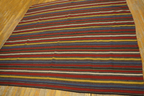 Colorful striped rug with red, blue, yellow, black, and white bands lies on light wooden floors.