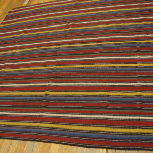 Flatweave rug with bright horizontal stripes of red, blue, yellow, and black on light wood flooring.