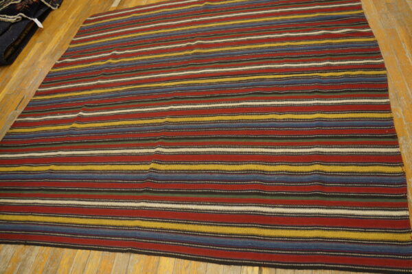 Flatweave rug with bright horizontal stripes of red, blue, yellow, and black on light wood flooring.