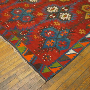 Red rug featuring vibrant geometric medallions and zigzag borders on wide plank wooden flooring.