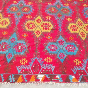 Flat woven rug with a bright red field and large yellow and blue geometric medallion patterns.