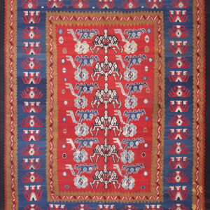 Red flatweave rug with complex blue, white, and tan geometric patterns and multiple borders.