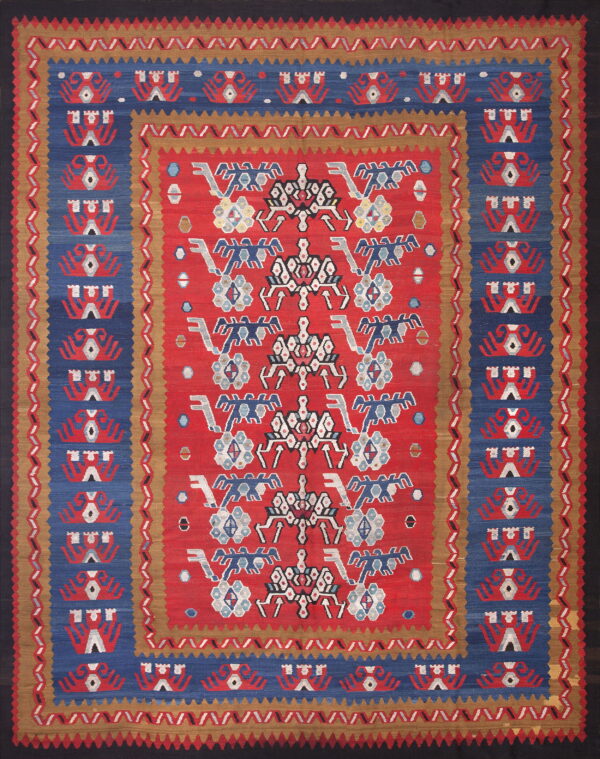 Red flatweave rug with complex blue, white, and tan geometric patterns and multiple borders.