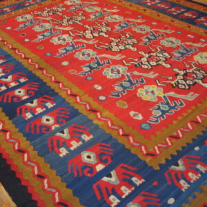 Flat-weave rug with a red center field and blue border featuring stylized figures on wood planks.