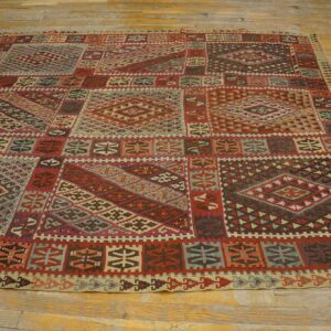 Low-pile geometric rug with red, teal, and brown patterns covers rustic yellow wood flooring.