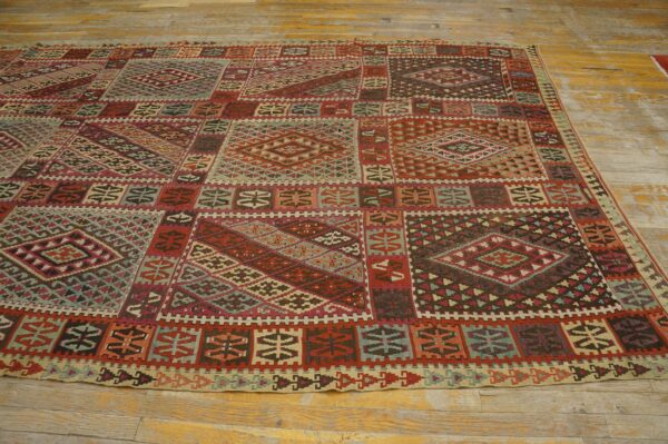 Low-pile geometric rug with red, teal, and brown patterns covers rustic yellow wood flooring.