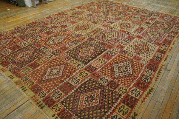 Large geometric rug in reds, browns, and cream hues on light natural wood plank flooring.