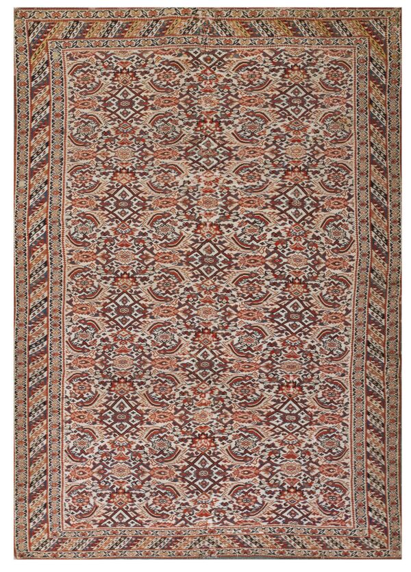 Cream rug with a busy traditional pattern in deep red, burnt orange, brown, and navy accents.