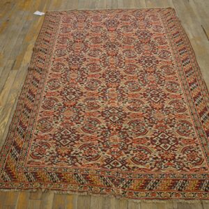 Low-pile runner rug featuring dense red, orange, and cream patterns on patchy, distressed wood flooring.