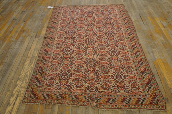 Low-pile runner rug featuring dense red, orange, and cream patterns on patchy, distressed wood flooring.