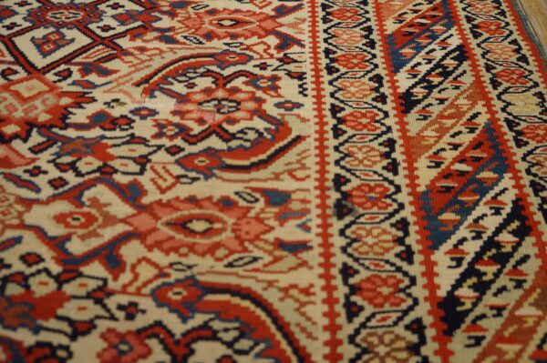 Low-pile rug detail featuring ivory ground with complex geometric designs in red and navy blue.