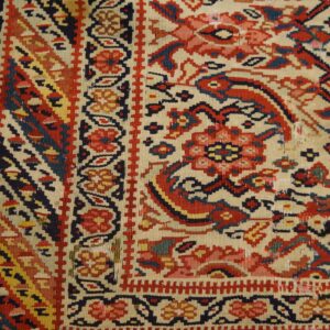 Detailed flat-weave rug in cream, red, blue, and yellow with intricate geometric and floral motifs.