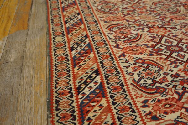 The rug's detailed red and blue geometric pattern is seen next to distressed light wood flooring.
