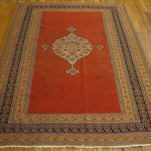 Terracotta rug featuring a large ornate central medallion and complex multicolored borders on a wood floor.