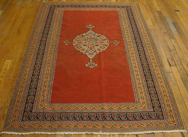 Terracotta rug featuring a large ornate central medallion and complex multicolored borders on a wood floor.