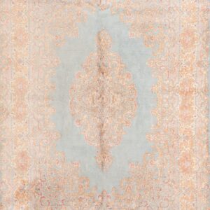 Ornate medallion rug featuring dusty blue, tan, and faded pink designs rests on dark wood planks.