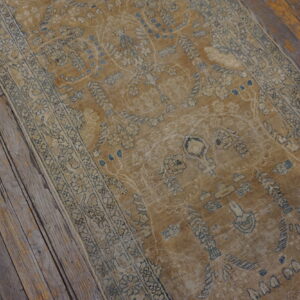 Faded ochre runner rug with blue and cream traditional patterns covers rustic, weathered wood floors.