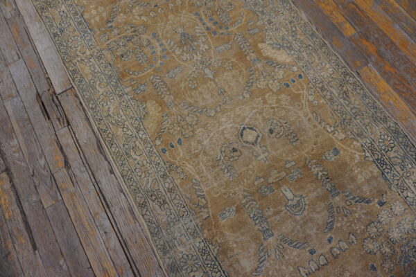 Faded ochre runner rug with blue and cream traditional patterns covers rustic, weathered wood floors.