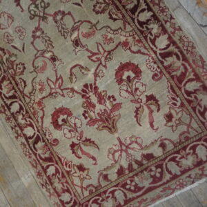 A distressed sage and burgundy floral rug runner lies diagonally on rustic gray plank flooring.