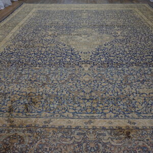 Expansive blue and cream traditional rug with a detailed floral pattern displayed on wood floorboards.