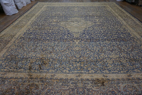 Expansive blue and cream traditional rug with a detailed floral pattern displayed on wood floorboards.