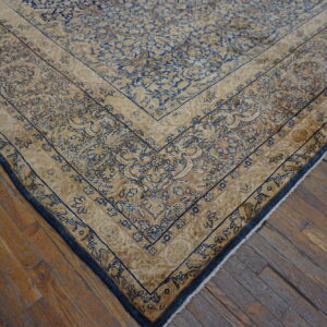 Ornate blue and beige patterned rug border lying on worn, narrow plank hardwood flooring.