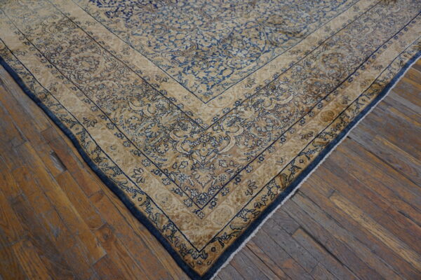 Ornate blue and beige patterned rug border lying on worn, narrow plank hardwood flooring.