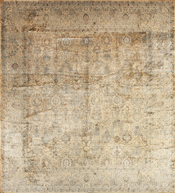 Distressed traditional rug in muted beige and blue/grey features an intricate, faded design.