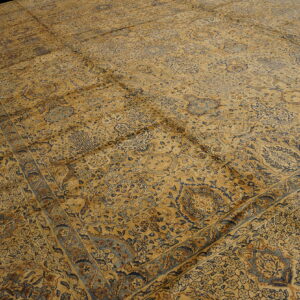 Detailed view of a gold and blue traditional rug with intricate floral patterns and wide borders.