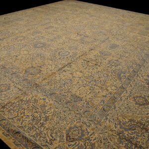 Large, low-pile rug featuring complex traditional patterns in slate blue and golden tan colors.