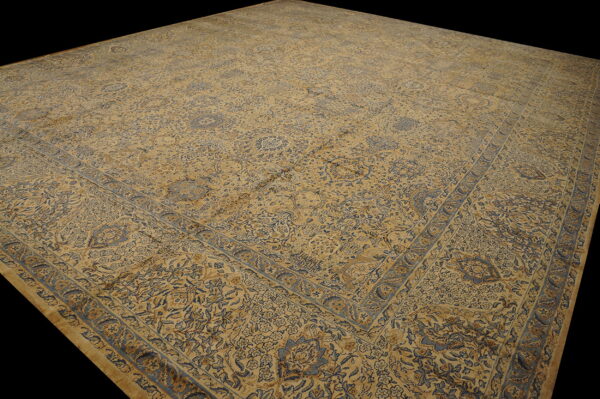 Large, low-pile rug featuring complex traditional patterns in slate blue and golden tan colors.