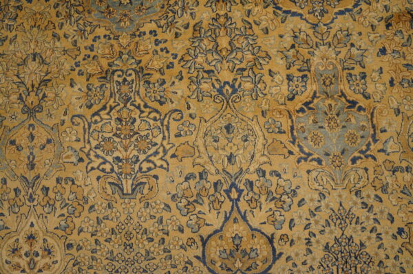 Low pile rug showing a detailed floral medallion pattern in golden yellow, navy blue, and light blue.