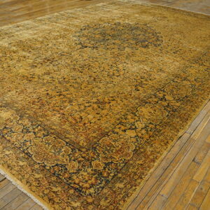 Traditional ochre and navy rug with detailed pattern covers distressed plank wood flooring.