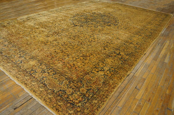Traditional ochre and navy rug with detailed pattern covers distressed plank wood flooring.